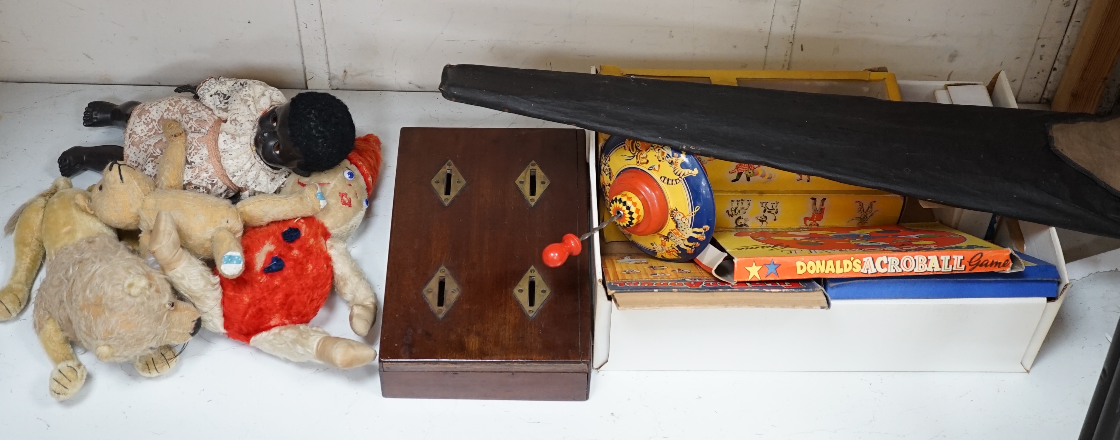 An early 20th century cased Bussey’s Hawk kite, a black walkie talkie doll, a four slot money box, an early Pelham puppet and two others, a hump backed teddy, together with various games and soft toys